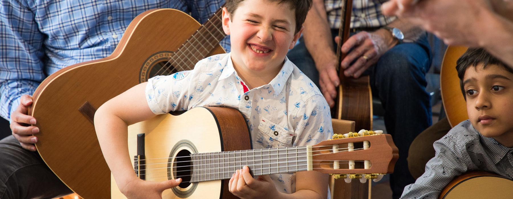 Guitar student performing with a big smile