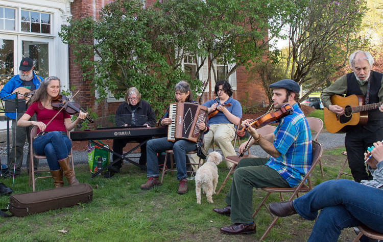 folks sitting outside playing fiddle tunes on various instruments