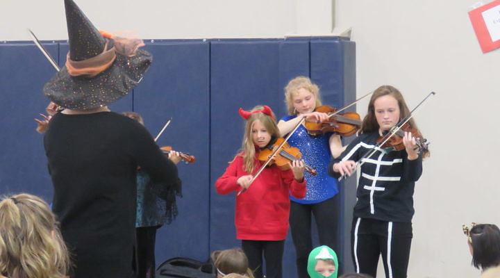 students in costume playing violin